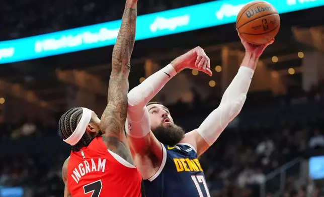 Denver Nuggets center Jonas Valančiūnas (17) jumps towards the basket as Toronto Raptors forward Brandon Ingram (3) defends during first half NBA action in Toronto on Wednesday Dec. 31, 2025. (Frank Gunn/The Canadian Press via AP)