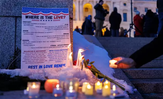 Candles burn around a poem written by Renee Nicole Good during a vigil honoring Good, outside the State Capitol, in St. Paul, Minn., Friday, Jan. 9, 2026, (Kerem Yücel/Minnesota Public Radio via AP)