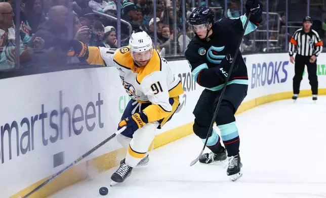 Nashville Predators center Steven Stamkos (91) and Seattle Kraken defenseman Cale Fleury, right, battle for a loose puck in the second period during an NHL hockey game Thursday, Jan. 1, 2026, in Seattle. (AP Photo/Kevin Ng)