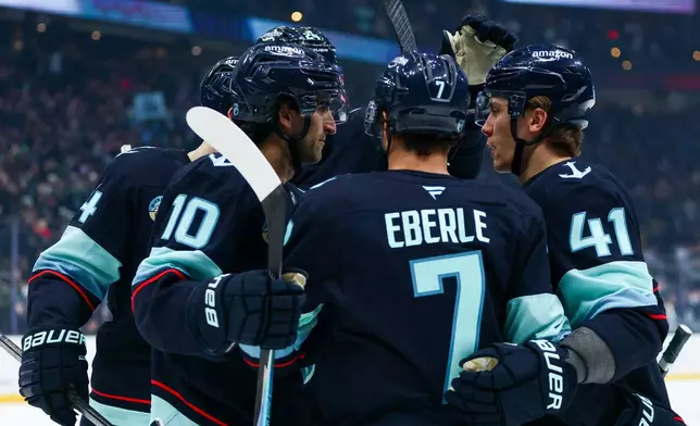 Seattle Kraken center Matty Beniers (10) is embraced by teammates after scoring in the first period against the Nashville Predators during an NHL hockey game Thursday, Jan. 1, 2026, in Seattle. (AP Photo/Kevin Ng)