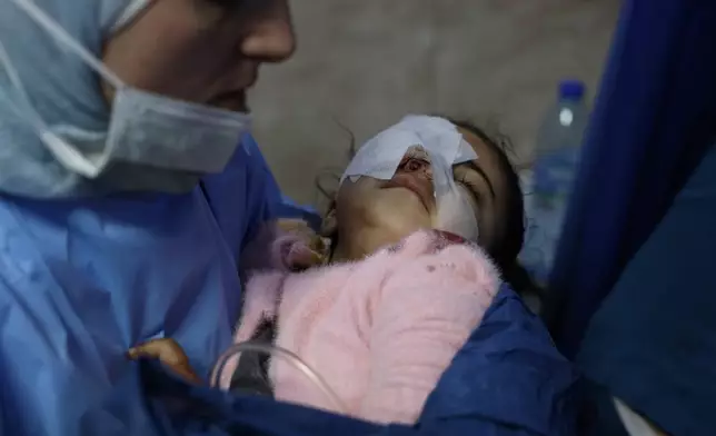 A nurse carries, Fatima al-Zahra Abu Sheikh, 4, a Syrian child who was wounded in clashes that broke out between Syrian government forces and Kurdish fighters in a contested area of the northern city of Aleppo, Syria, Tuesday, Jan. 6, 2026. (AP Photo/Omar Albam)