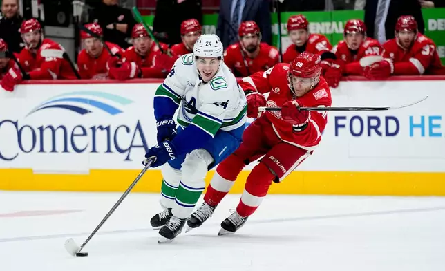 Vancouver Canucks defenseman Zeev Buium, left, moves the puck ahead of Detroit Red Wings right wing Patrick Kane during the first period of an NHL hockey game Thursday, Jan. 8, 2026, in Detroit. (AP Photo/Ryan Sun)