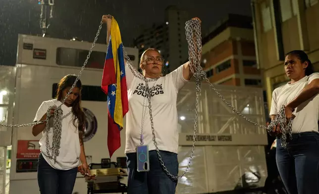 Relatives of people they consider to be detained for political reasons protest holding chains in front of police guarding the Zona 7 Bolivarian National Police detention center in Caracas, Venezuela, Friday, Jan. 30, 2026, on the same day acting President Delcy Rodríguez announced an amnesty bill that could lead to the release of hundreds of prisoners, including opposition leaders, journalists and human rights activists detained for political reasons. (AP Photo/Ariana Cubillos)