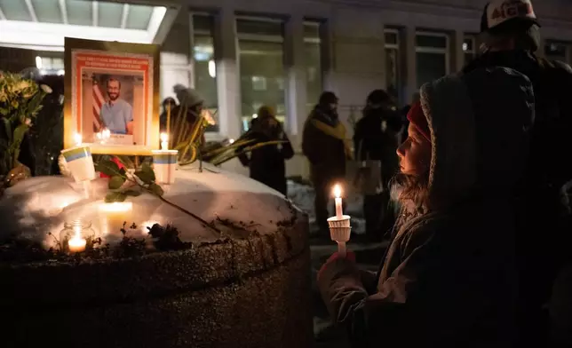 A young girl looks at a memorial for Alex Pretti during a vigil outside the Veterans Affairs headquarters, Wednesday, Jan. 28, 2026 in Washington. (AP Photo/Kevin Wolf)