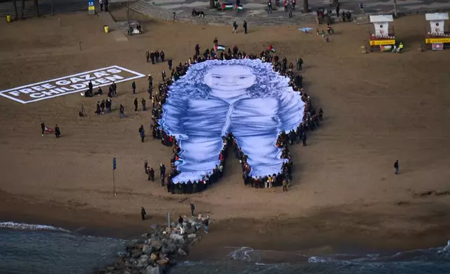 People hold a giant portrait of Hind Rajab, a five-year-old Palestinian girl who was killed during the war in Gaza, on a beach in Barcelona, Spain, Thursday, Jan. 29, 2026. (AP Photo/Emilio Morenatti)