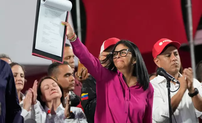 Venezuela's acting President Delcy Rodriguez takes part in a rally holding up a copy of a new law after lawmakers approved legislation opening the nation's oil sector to privatization, at the Miraflores Palace in Caracas, Venezuela, Thursday, Jan. 29, 2026. (AP Photo/Ariana Cubillos)