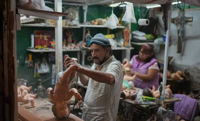 Adolfo Vertiz repairs a figurine of Baby Jesus ahead of "Dia de la Candelaria," or Candlemas, in Mexico City, Thursday, Jan. 29, 2026. (AP Photo/Eduardo Verdugo)