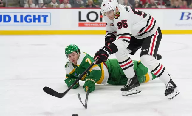 Chicago Blackhawks right wing Ilya Mikheyev (95) and Minnesota Wild defenseman Brock Faber (7) reach for the puck during the second period of an NHL hockey game, Tuesday, Jan. 27, 2026, in St. Paul, Minn. (AP Photo/Abbie Parr)