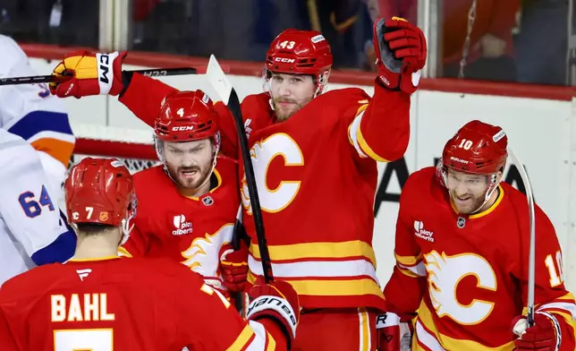 Calgary Flames' Adam Klapka, top, celebrates his goal with teammates Rasmus Andersson (4), Kevin Bahl (7), and Jonathan Huberdeau, right, during the second period of an NHL hockey game against the New York Islanders, in Calgary, Alberta, Saturday, Jan. 17, 2026. (Larry MacDougal/The Canadian Press via AP)