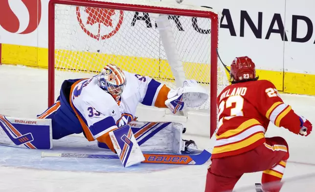 New York Islanders goalie David Rittich, left, is scored on by Calgary Flames' Justin Kirkland during second period NHL hockey action in Calgary, Alta., Saturday, Jan. 17, 2026. (Larry MacDougal/The Canadian Press via AP)