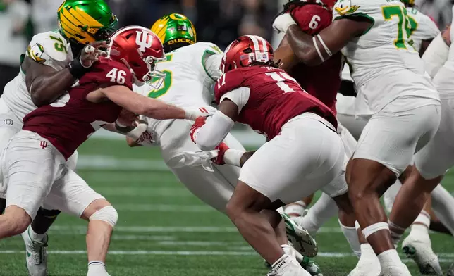 Oregon quarterback Dante Moore (5) is sacked by Indiana linebacker Isaiah Jones (46) and defensive lineman Daniel Ndukwe (17) during the first half of the Peach Bowl NCAA college football playoff semifinal, Friday, Jan. 9, 2026, in Atlanta. (AP Photo/Mike Stewart)