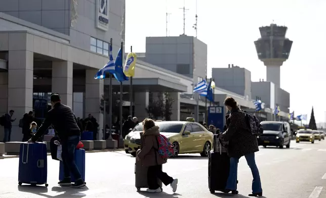 Passengers make their way to Athens' Eleftherios Venizelos international airport in Athens, Greece, Sunday, Jan. 4, 2026, as many flights were disrupted across Greece. (AP Photo/Yorgos Karahalis)
