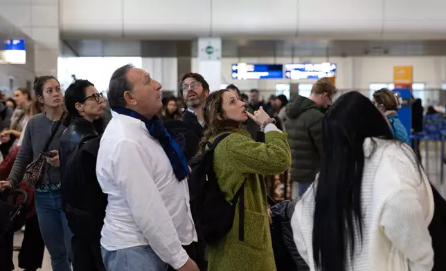 Passengers check a flight information board inside Athens' Eleftherios Venizelos international airport in Athens, Greece, Sunday, Jan. 4, 2026, as many flights were disrupted across Greece. (AP Photo/Yorgos Karahalis)