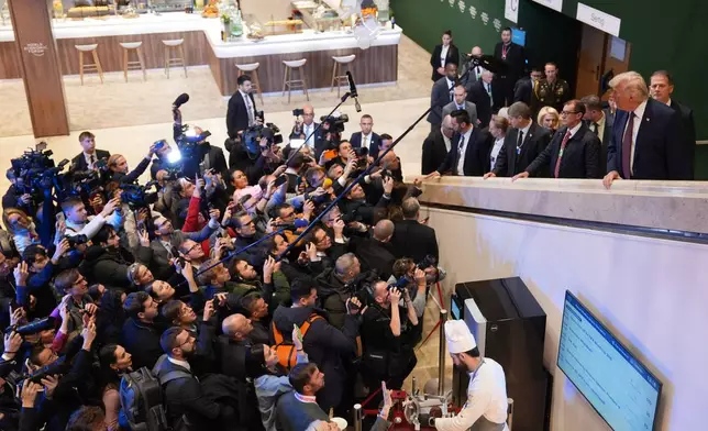 Journalist ask questions to President Donald Trump, right, as he walks up a stairwell during the Annual Meeting of the World Economic Forum in Davos, Switzerland, Thursday, Jan. 22, 2026. (AP Photo/Evan Vucci)