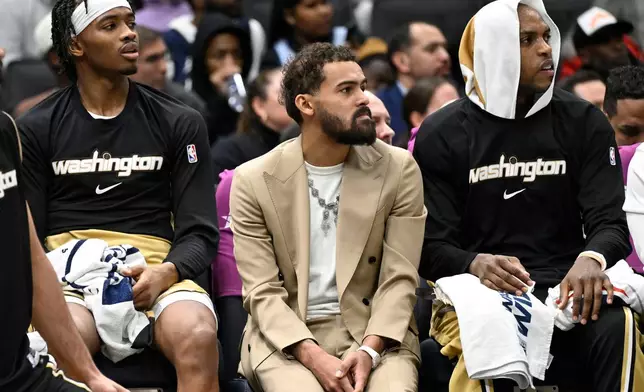Washington Wizards newly acquired point guard Trae Young, center, sits on the bench in street clothes between guard Bilal Coulibaly, left, and forward Khris Middleton during the first half of an NBA basketball game against the New Orleans Pelicans, Friday, Jan. 9, 2026, in Washington. (AP Photo/John McDonnell)