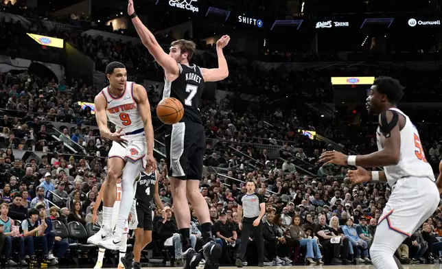New York Knicks guard Kevin McCullar Jr. (9) passes to Knicks center Ariel Hukporti as he is guarded by San Antonio Spurs center Luke Kornet (7) during the first half of an NBA basketball game, Wednesday, Dec. 31, 2025, in San Antonio. (AP Photo/Darren Abate)