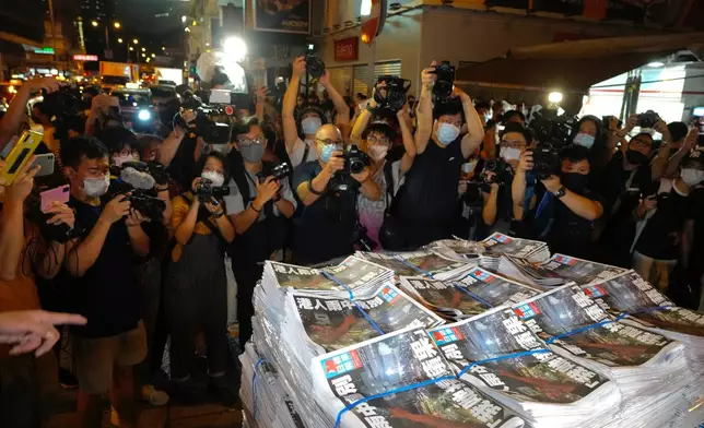FILE - Members of the media take photos of stacks of the last issue of Apple Daily as they arrive at a newspaper booth in Hong Kong, June 24, 2021. (AP Photo/Vincent Yu, File)