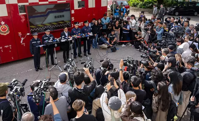FILE- Hong Kong Secretary for Security Chris Tang, third from left at rear, speaks to the members of media after a deadly fire at Wang Fuk Court, a residential estate in the Tai Po district of Hong Kong's New Territories, Nov. 28, 2025. (AP Photo/Chan Long Hei, File)