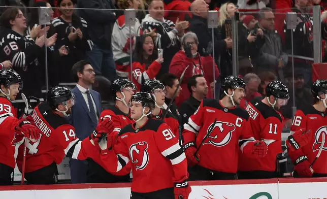 New Jersey Devils center Dawson Mercer (91) high-fives teammates after a goal in the first period of an NHL hockey game against the Carolina Hurricanes, Sunday, Jan. 4, 2026, in Newark, N.J. (AP Photo/Heather Khalifa)
