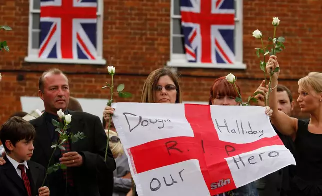 FILE - Relatives of British Army Private Douglas Halliday, of the 1st Battalion The Mercian Regiment, one of the seven British soldiers killed in Afghanistan, line a street as his coffin is driven through the town of Wootton Bassett, England, following repatriation, Tuesday, June 29, 2010. (AP Photo/Lefteris Pitarakis, file)