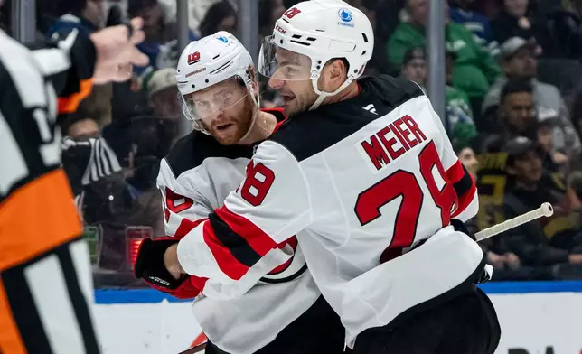 New Jersey Devils' Connor Brown (16) celebrates his goal against the Vancouver Canucks with Timo Meier (28) during the second period of an NHL hockey game in Vancouver, British Columbia, Friday, Jan. 23, 2026. (Ethan Cairns/The Canadian Press via AP)