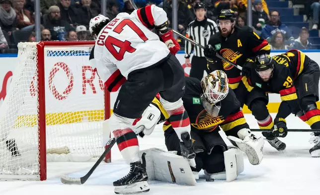 Vancouver Canucks goaltender Kevin Lankinen (32) stops New Jersey Devils' Paul Cotter (47) during the second period of an NHL hockey game in Vancouver, British Columbia, Friday, Jan. 23, 2026. (Ethan Cairns/The Canadian Press via AP)