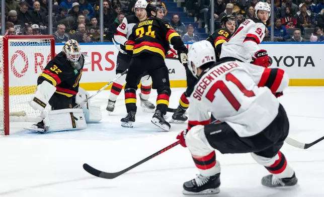 Vancouver Canucks goaltender Kevin Lankinen (32) stops New Jersey Devils' Jonas Siegenthaler (71) during the second period of an NHL hockey game in Vancouver, British Columbia, Friday, Jan. 23, 2026. (Ethan Cairns/The Canadian Press via AP)