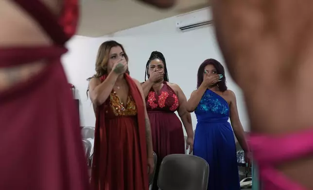 Inmates warm up their voices backstage as they prepare to sing in the Voice of Freedom rehabilitation program singing contest at the Djanira Dolores de Oliveira women's penitentiary in Rio de Janeiro, Friday, Jan. 23, 2026. (AP Photo/Silvia Izquierdo)