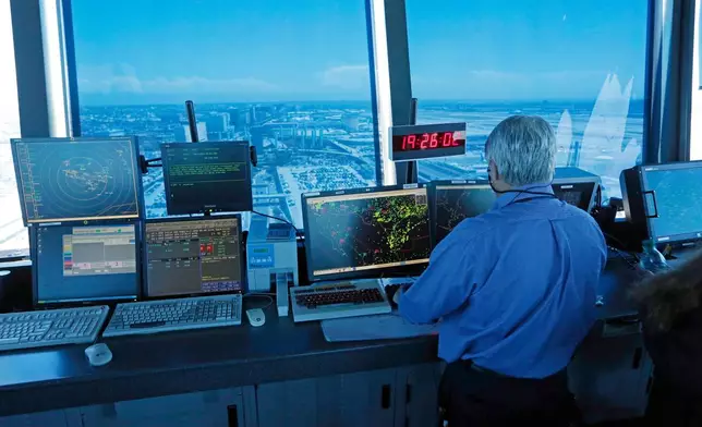 FILE - In this Sept. 4, 2013 photo, an air traffic controller works at computer screens and a digital clock showing Coordinated Universal Time (UTC), or Zulu time, is seen in this view looking eastward from the control tower at Los Angeles International Airport (LAX). (AP Photo/Reed Saxon, File)