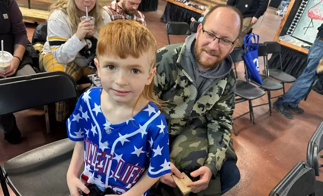 Ben Barley, a 7-year-old first-grader from Red Lion, Pa., waits with his father, Robert Barley, for the start of a mullet judging contest at the Pennsylvania Farm Show in Harrisburg on Monday, Jan. 12, 2026. (AP Photo/Mark Scolforo)