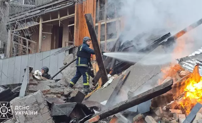 In this photo, provided by the Ukrainian Emergency Service, emergency services personnel work to extinguish a fire following a Russian missile attack in Kharkiv, Ukraine, Friday, Jan. 2, 2026. (Ukrainian Emergency Service via AP)