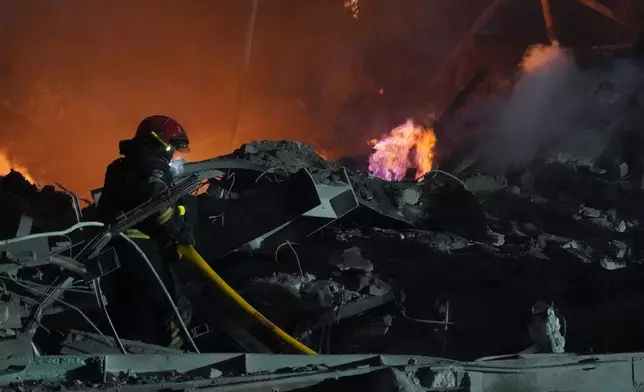 Emergency services personnel work to extinguish a fire following a Russian missile attack in Kharkiv, Ukraine, Friday, Jan. 2, 2026.(AP Photo/Andrii Marienko)