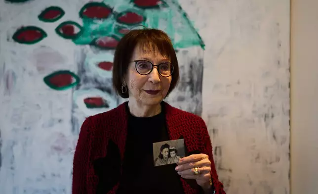 Holocaust survivor Ilana Shalem-Kantorowics, born in the Nazi Bergen-Belsen concentration camp, holds a photo of her with her mother Lola taken in the camp in 1946, in Tel Aviv, Israel, Jan. 26, 2026. (AP Photo/Ariel Schalit)
