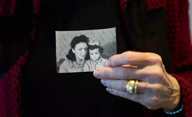 Holocaust survivor Ilana Shalem-Kantorowics born in the Nazi Bergen-Belsen concentration camp holds a photo of her with her mother Lola in the camp in 1946, in Tel Aviv, Israel, Jan. 26, 2026. (AP Photo/Ariel Schalit)