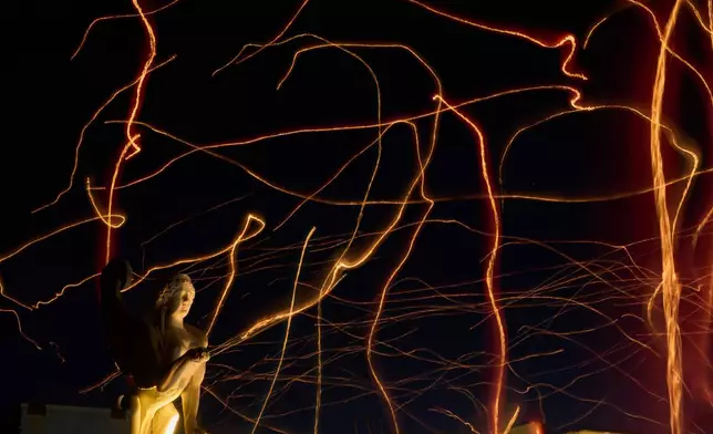 FILE - This photo taken with low shutter speed shows tracers cross the sky made by floating lanterns during an event coined The night of wishes, in front of the Athens City Hall, Greece, Dec. 26, 2025. (AP Photo/Petros Giannakouris File)