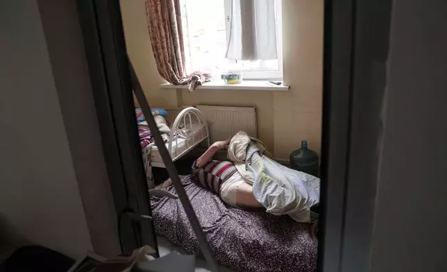 FILE - En elderly man lies on the floor at a hospice after it was damaged after a Russian strike on Kyiv, Ukraine, Dec. 27, 2025. (AP Photo/Evgeniy Maloletka, File)