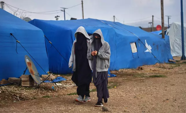Two women walk among tents at Roj camp, one of the detention facilities holding thousands of Islamic State group members and their families, in the al-Malikiyah area of northeastern Syria, Thursday, Jan. 29, 2026. (AP Photo/Baderkhan Ahmad)