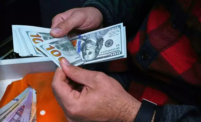 FILE- A currency exchange bureau worker counts U.S. dollars at Ferdowsi square, Tehran's go-to venue for foreign currency exchange, in downtown Tehran, Iran, April 5, 2025. (AP Photo/Vahid Salemi, File)