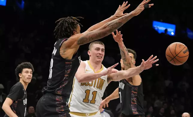 Boston Celtics' Payton Pritchard (11) passes away from Brooklyn Nets' Nic Claxton (33) and Michael Porter Jr. (17) during the second overtime of an NBA basketball game Friday, Jan. 23, 2026, in New York. (AP Photo/Frank Franklin II)