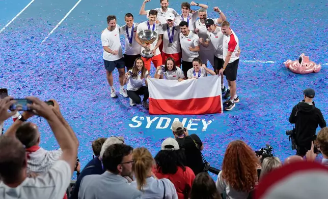 Teammembers from Poland celebrate with their trophy after defeating Switzerland in the final at the United Cup tennis tournament in Sydney, Monday, Jan. 12, 2026. (AP Photo/Rick Rycroft)