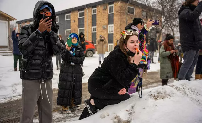 People record and react to federal agents arresting people, Wednesday, Jan. 21, 2026, in Minneapolis. (AP Photo/Angelina Katsanis)