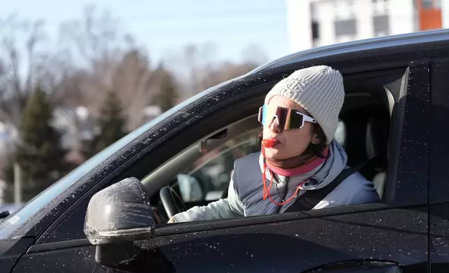 A woman uses a whistle as a convoy of Federal agents drive by on Friday, Jan. 23, 2026, in Minneapolis. (AP Photo/Angelina Katsanis)