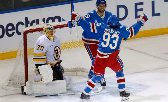 New York Rangers defenseman Matthew Robertson, top right, is congratulated by center Mika Zibanejad (93) as Boston Bruins goalie Joonas Korpisalo (70) looks on after Robertson scored the winning goal in overtime of an NHL hockey game Monday, Jan. 26, 2026, in New York. (AP Photo/John Munson)