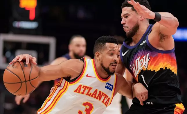 Atlanta Hawks guard CJ McCollum (3) drives against Phoenix Suns guard Devin Booker (1) during the first half of an NBA basketball game, Friday, Jan. 23, 2026, in Atlanta. (AP Photo/Mike Stewart)