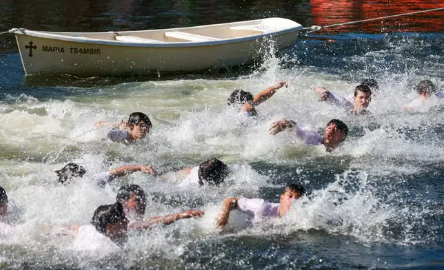 Cross divers swim quickly towards the cross during the annual cross dive in the Spring Bayou, part of the Epiphany celebration on Tuesday, Jan. 6, 2026, in Tarpon Springs, Fla. (Jefferee Woo/Tampa Bay Times via AP)