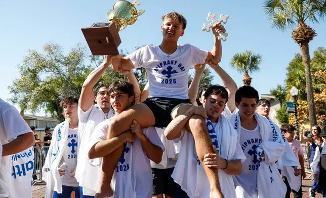 Athos Karistinos, 18, of Tarpon Springs, is carried by fellow cross divers as they celebrate his victory during the annual cross dive in the Spring Bayou, part of the Epiphany celebration on Tuesday, Jan. 6, 2026, in Tarpon Springs, Fla. (Jefferee Woo /Tampa Bay Times via AP)