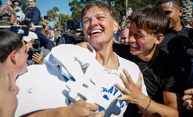 Athos Karistinos, 18, of Tarpon Springs, is congratulated by cross divers, friends and family, after he retrieves the cross during the annual cross dive in the Spring Bayou, part of the Epiphany celebration on Tuesday, Jan. 6, 2026, in Tarpon Springs, Fla. (Jefferee Woo /Tampa Bay Times via AP)
