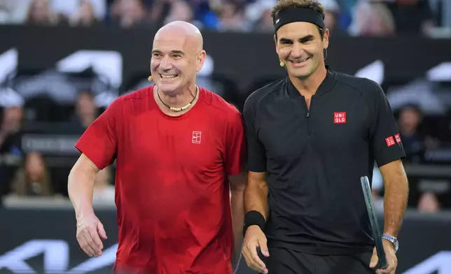 Roger Federer of Switzerland reacts with partner Andre Agassi, left, of the United States in their doubles match against Lleyton Hewitt and Pat Rafter of Australia during the Opening Ceremony for the Australian Open tennis championship in Melbourne, Australia, Saturday, Jan. 17, 2026. (AP Photo/Dita Alangkara)