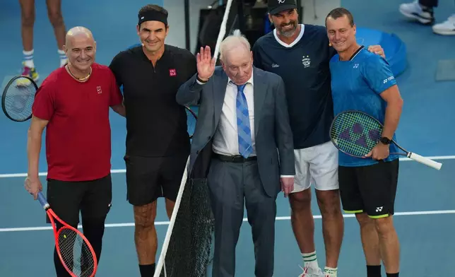 Rod Laver, centre, waves ahead of a doubles match between Roger Federer of Switzerland and Andre Agassi of the United States, left, and Lleyton Hewitt, right, and Pat Rafter of Australia during the Opening Ceremony for the Australian Open tennis championship in Melbourne, Australia, Saturday, Jan. 17, 2026.(AP Photo/Dita Alangkara)