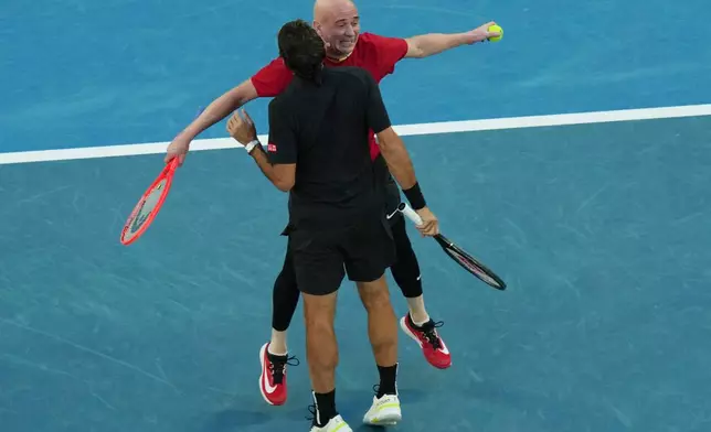 Roger Federer of Switzerland and Andre Agassi, right, of the United States react in their doubles match against Lleyton Hewitt and Pat Rafter of Australia during the Opening Ceremony for the Australian Open tennis championship in Melbourne, Australia, Saturday, Jan. 17, 2026 (AP Photo/Dar Yasin)